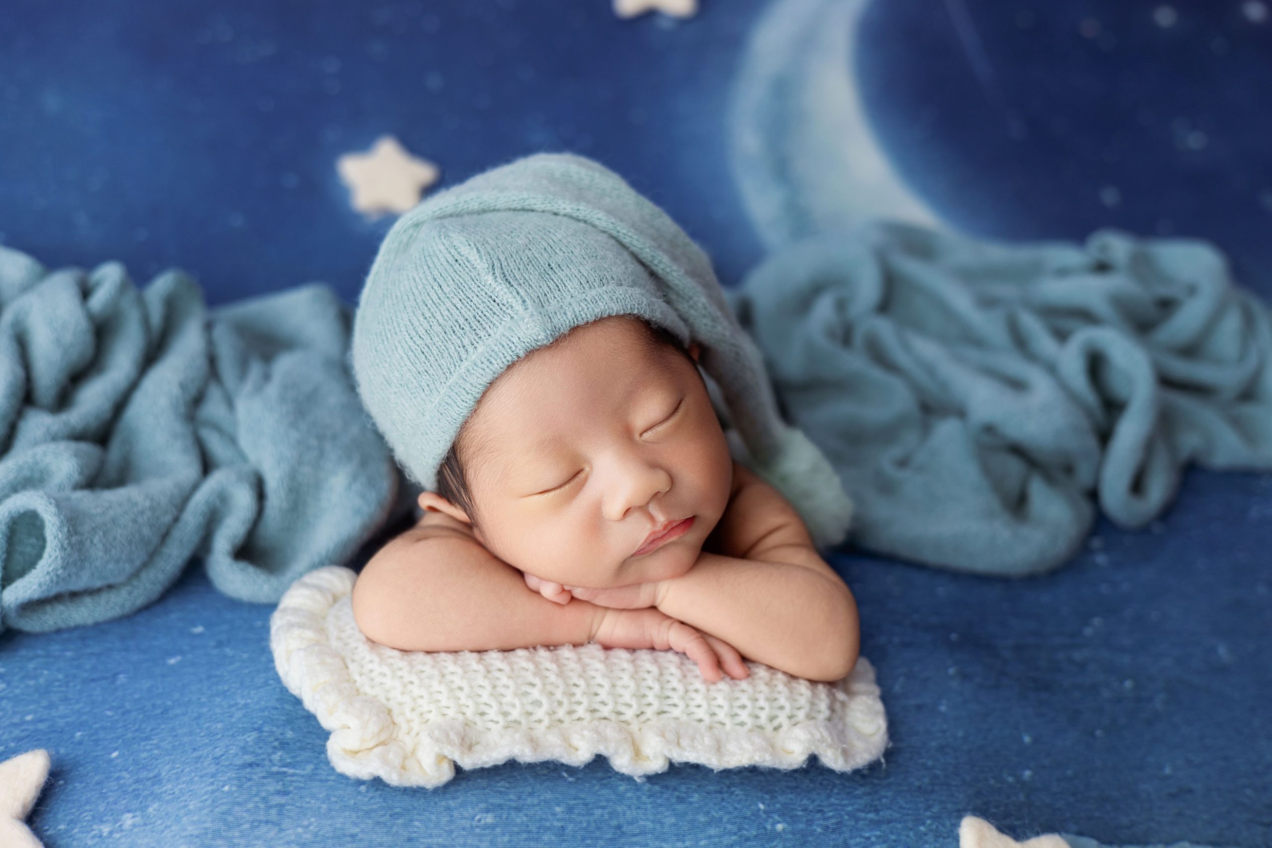 Bébé endormi bonnet bleu fond lune.