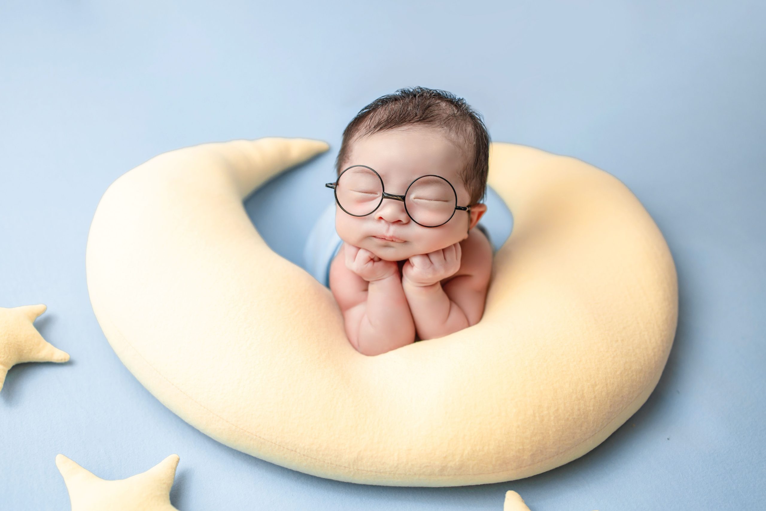 Nouveau-né lunettes posé dans coussin lune.