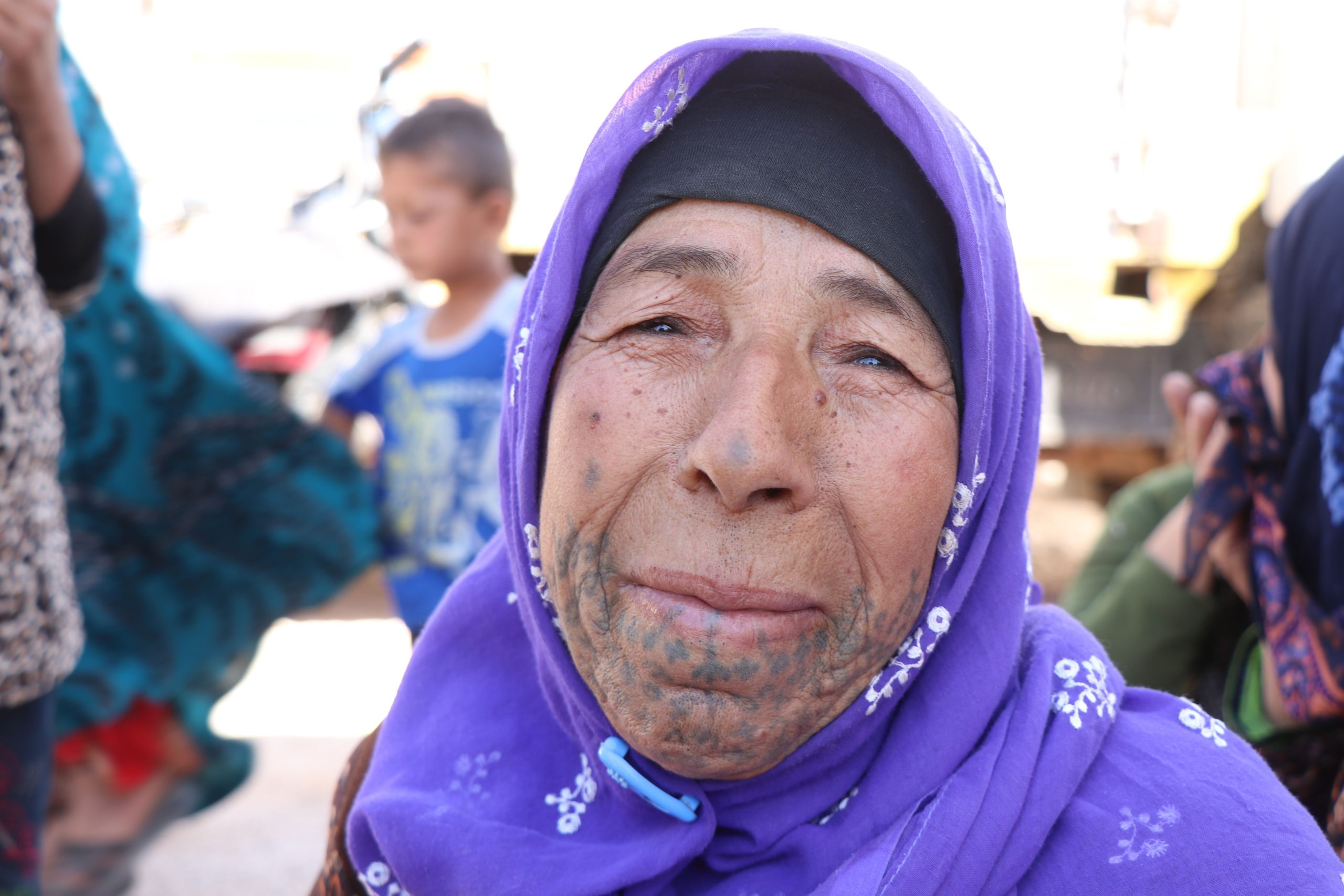 Femme âgée avec tatouage facial berbère et foulard violet