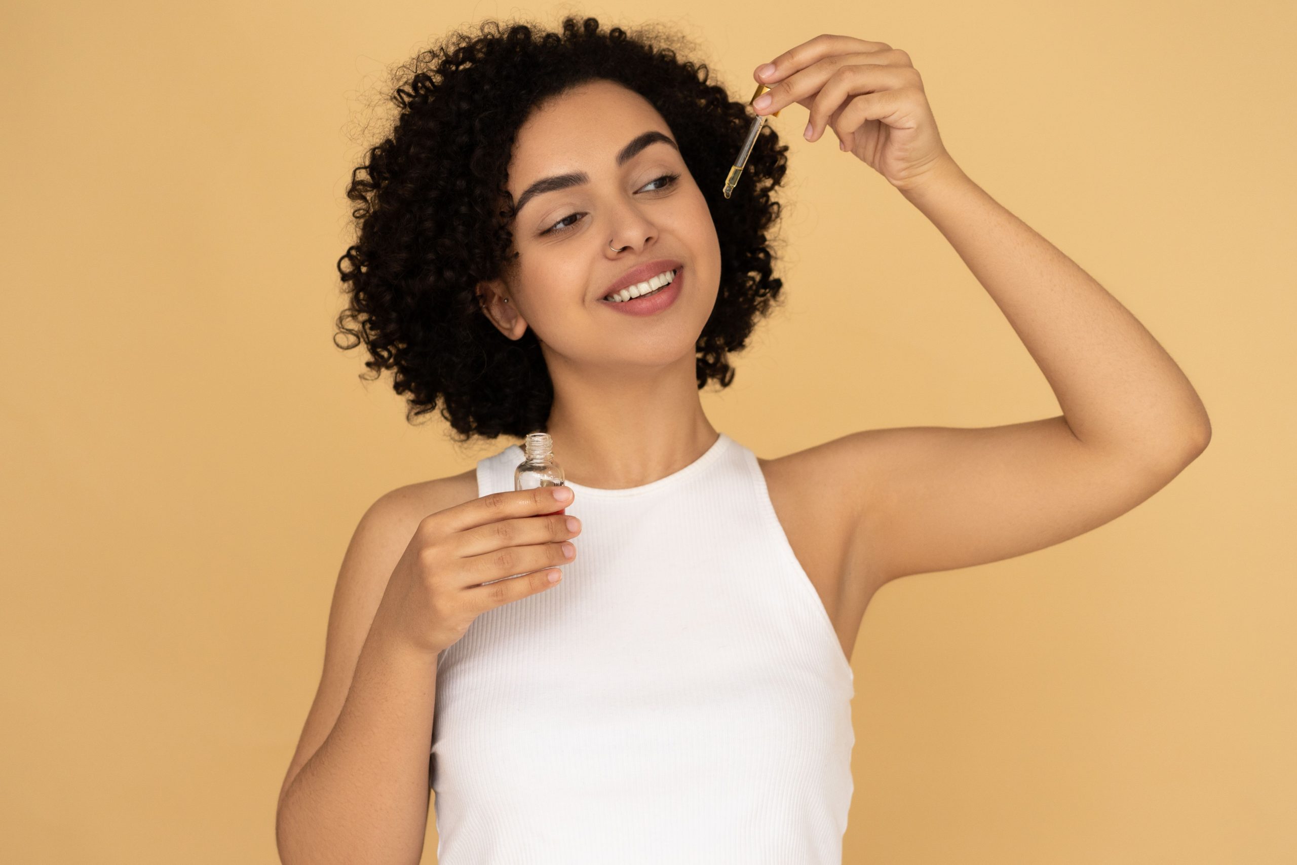 Femme souriante appliquant huile essentielle cheveux