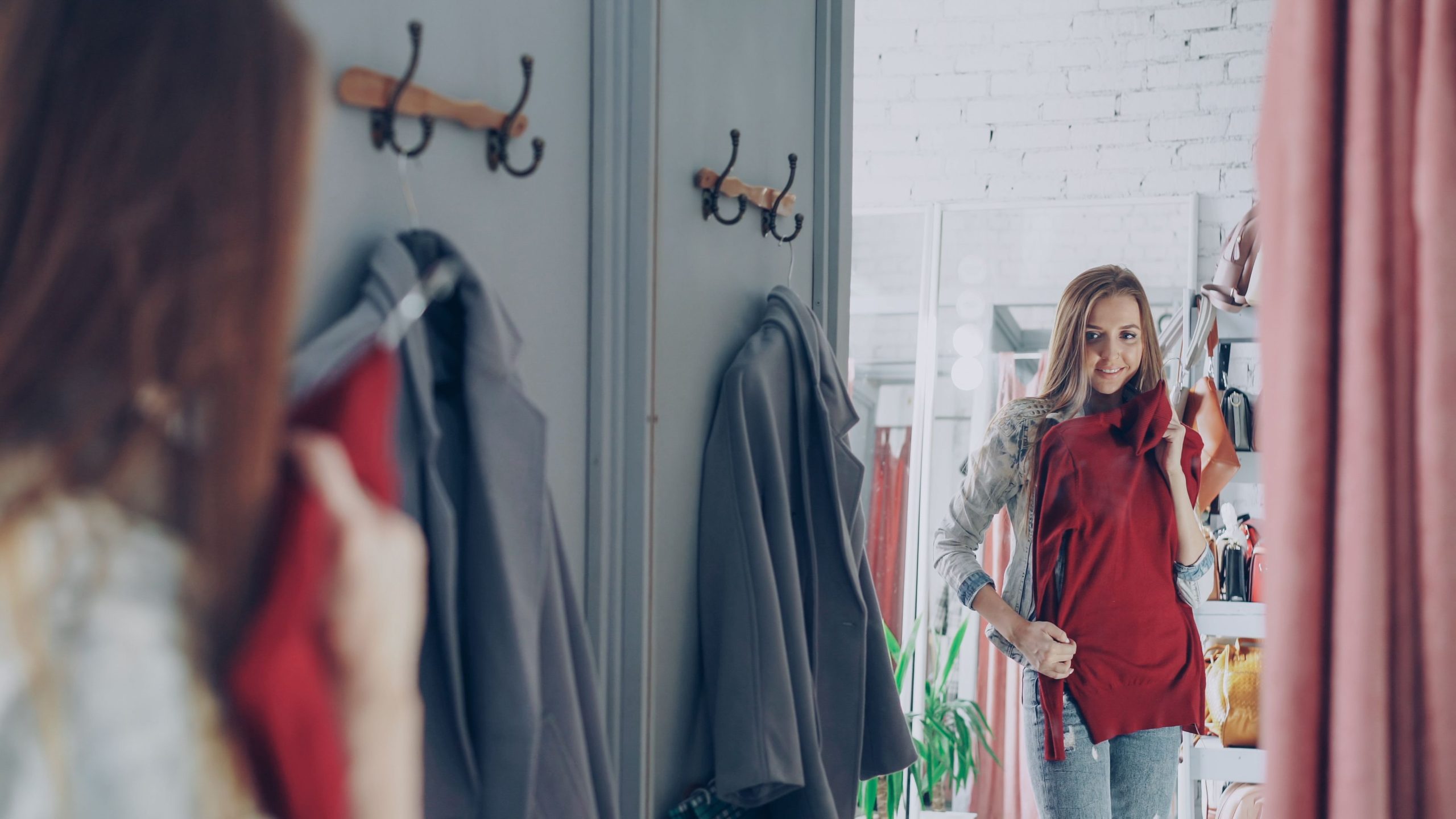 Femme souriante tenant une robe rouge boutique