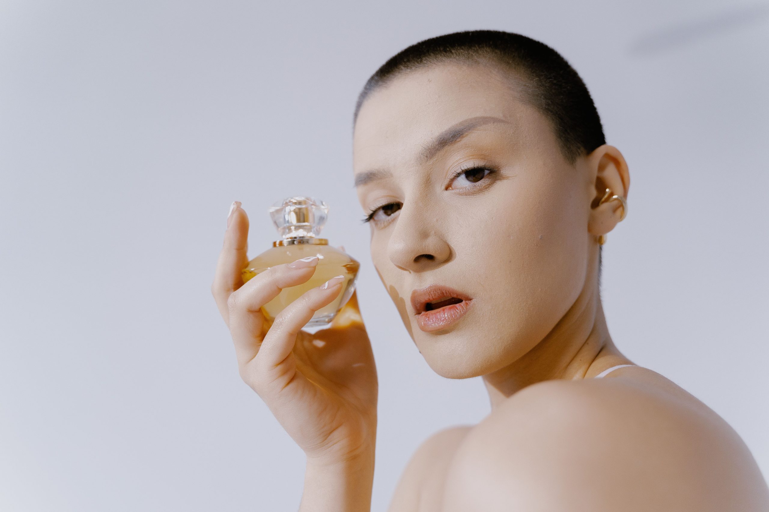 Femme cheveux courts tenant flacon parfum élégant