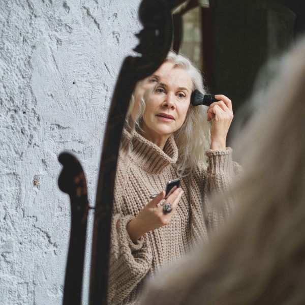Femme mature se maquille devant son miroir