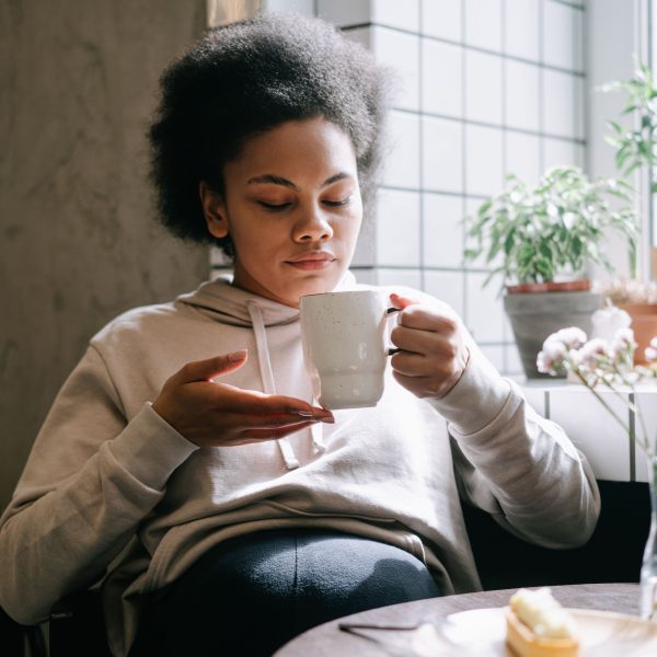Femme savourant une tasse de thé près d'une fenêtre