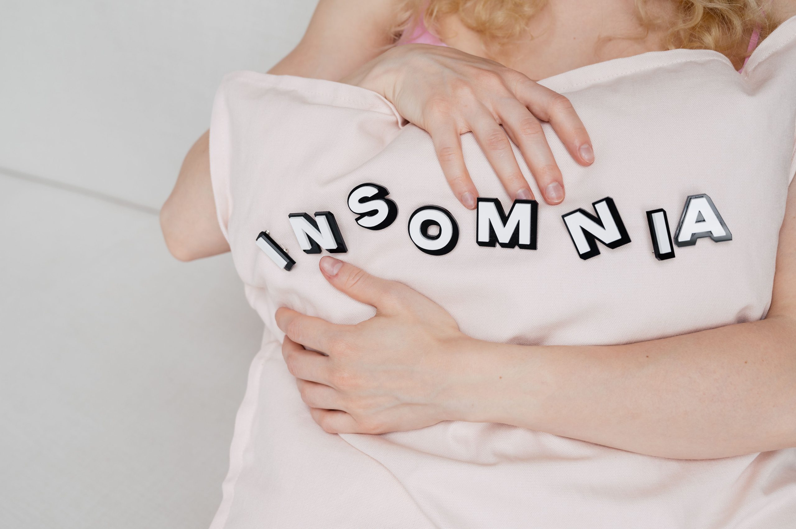 Femme tenant un oreiller avec texte insomnie