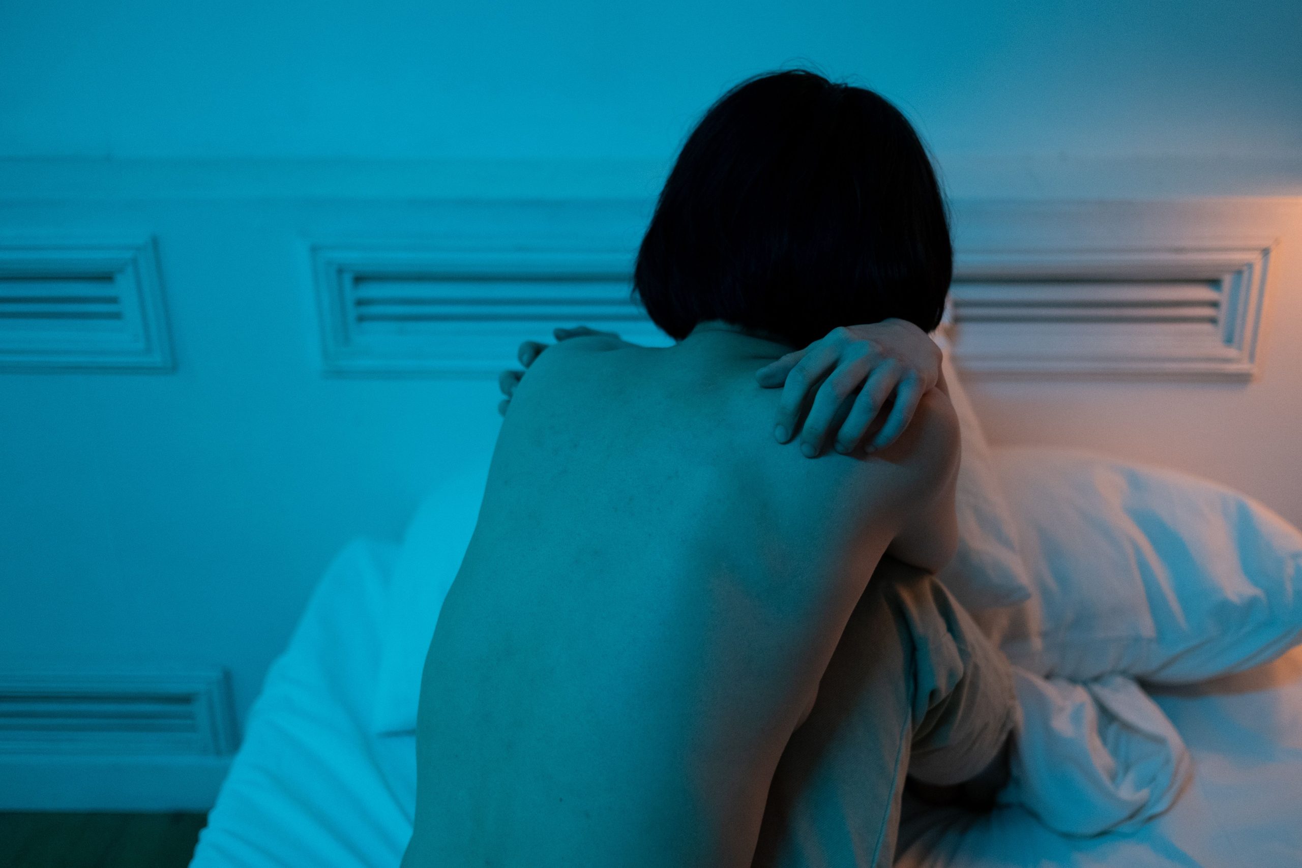 Femme seule assise sur son lit sombre