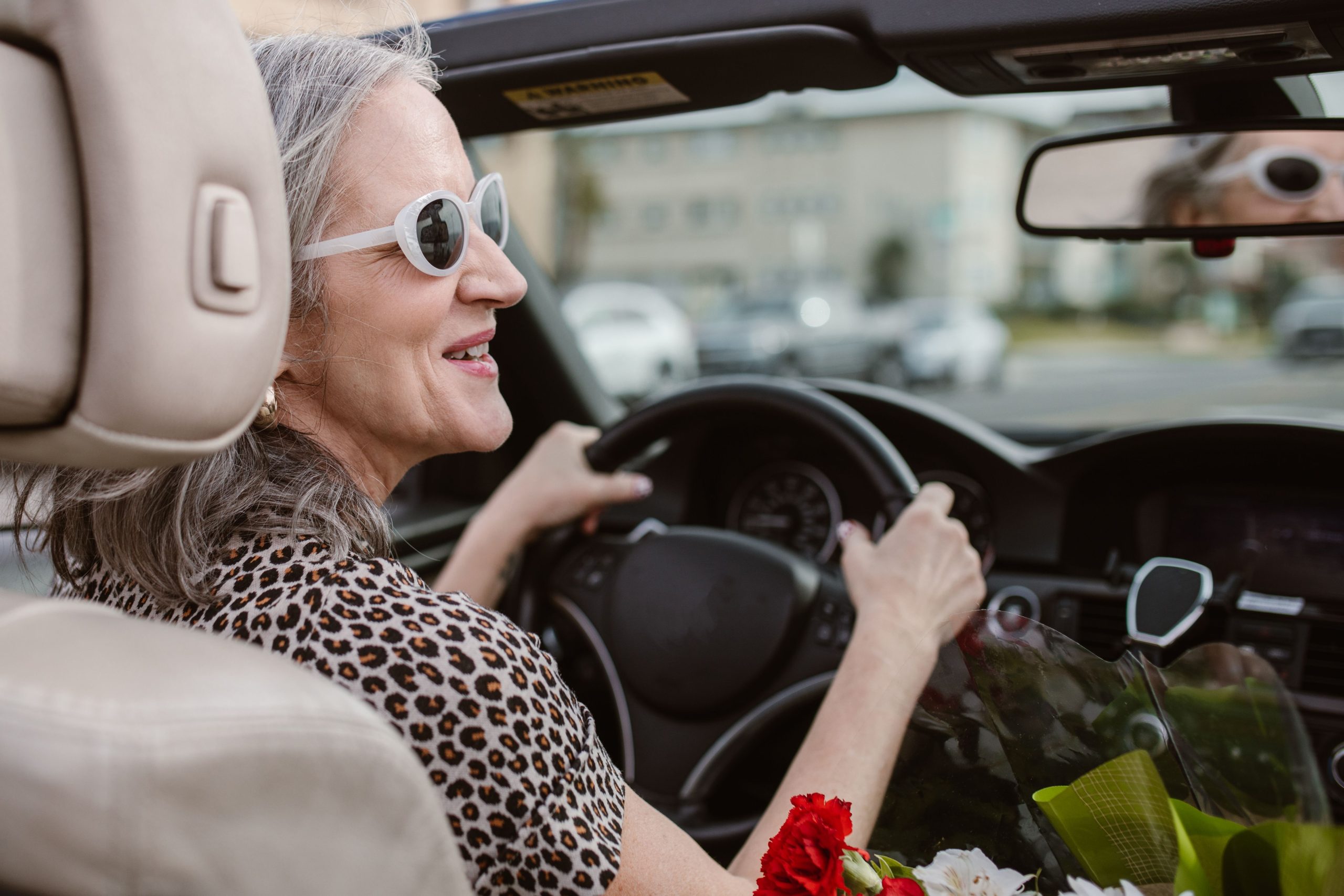 Femme senior conduisant cabriolet souriante