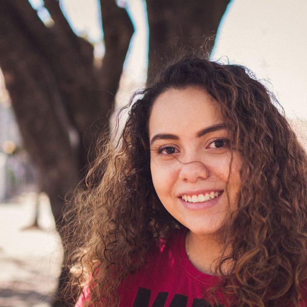 Jeune femme souriante aux cheveux bouclés en extérieur