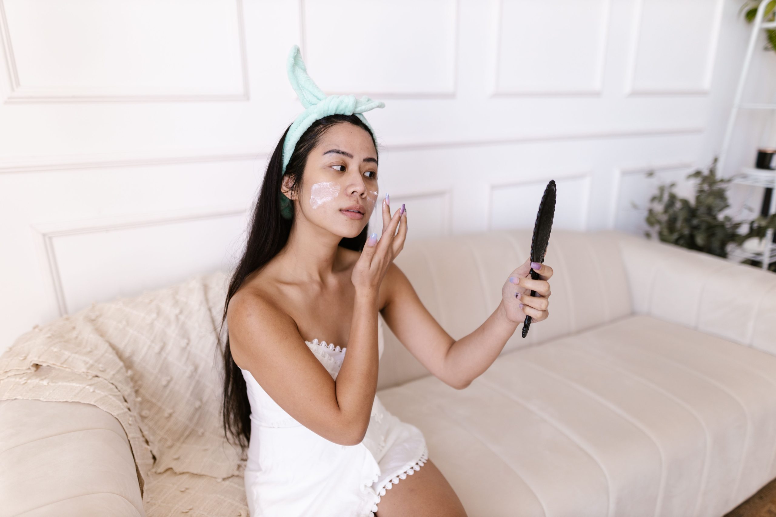 Femme asiatique appliquant crème hydratante au miroir