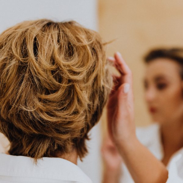Femme coiffant ses cheveux courts devant un miroir