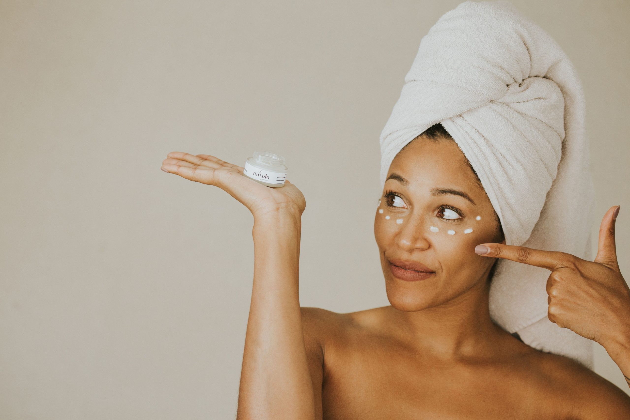 Femme souriante appliquant crème visage après douche