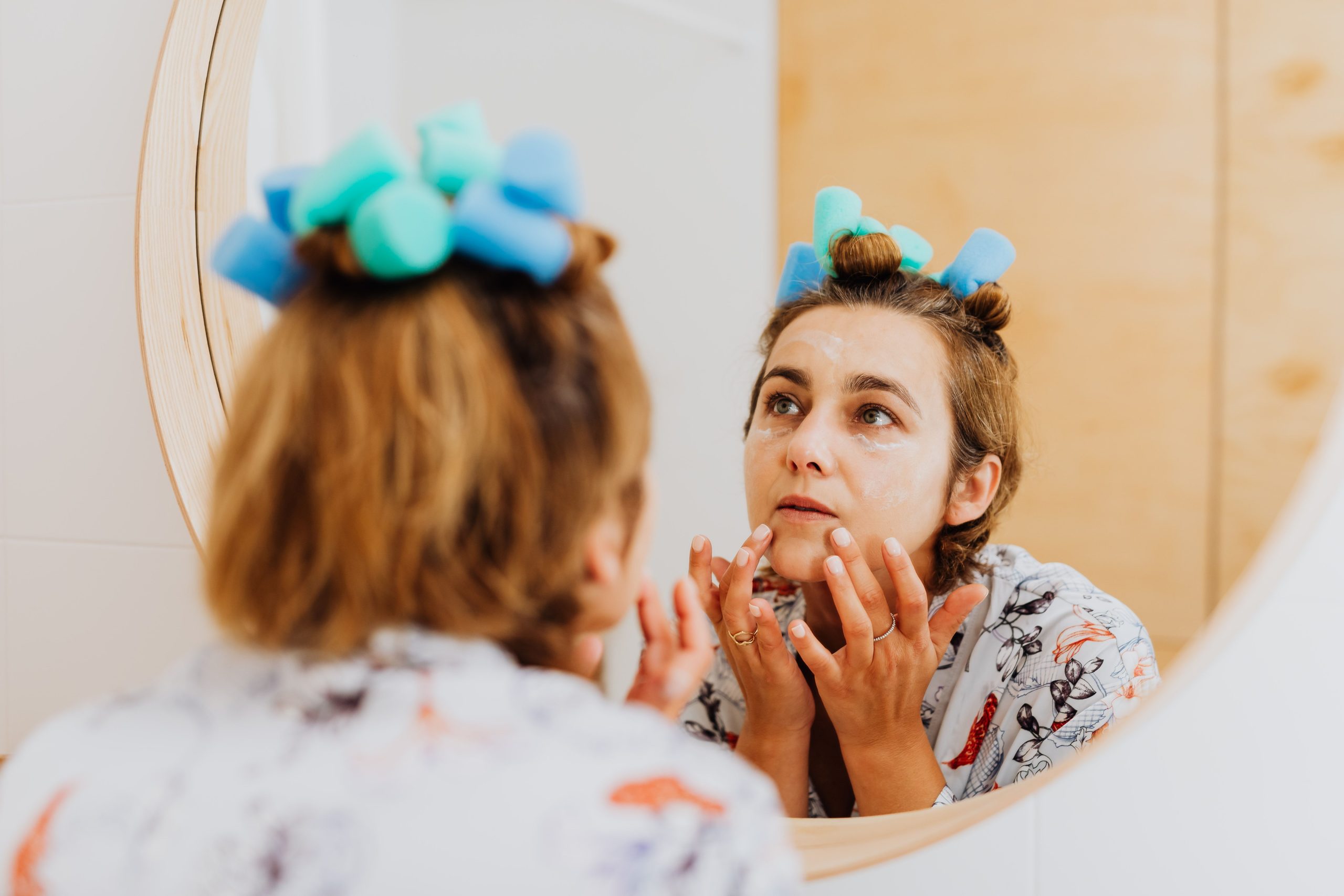 Femme avec bigoudis appliquant soin du visage