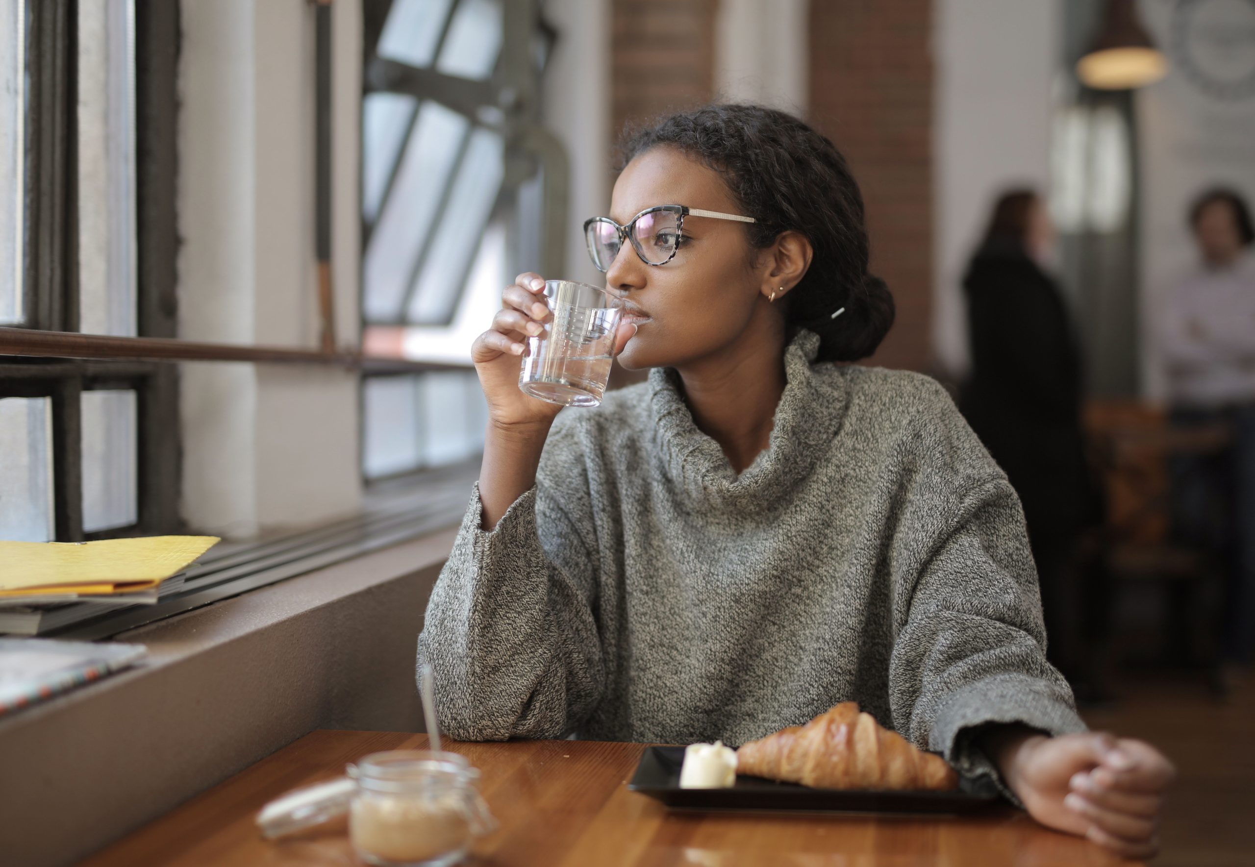 Femme souriante boit de l'eau au café