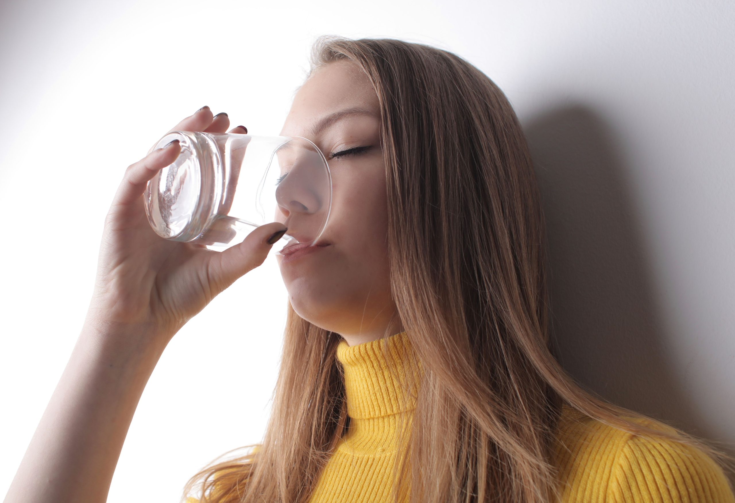 Femme en pull jaune boit de l'eau fraîche