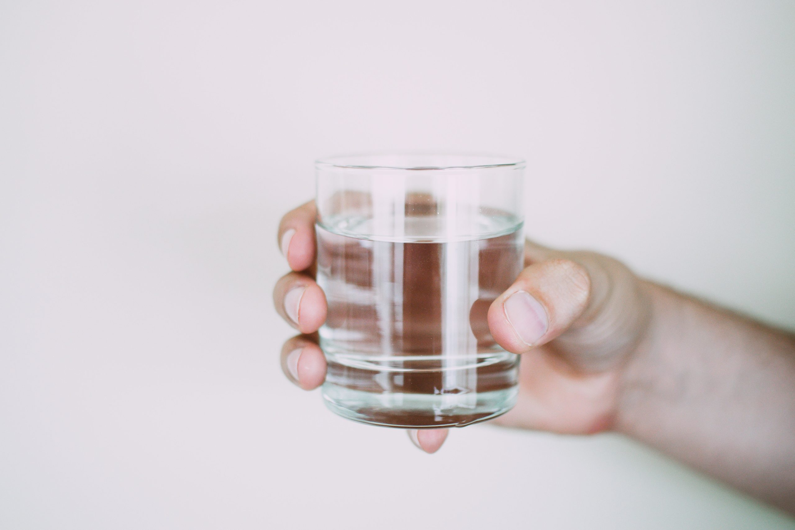 Main tenant un verre d'eau cristalline transparente